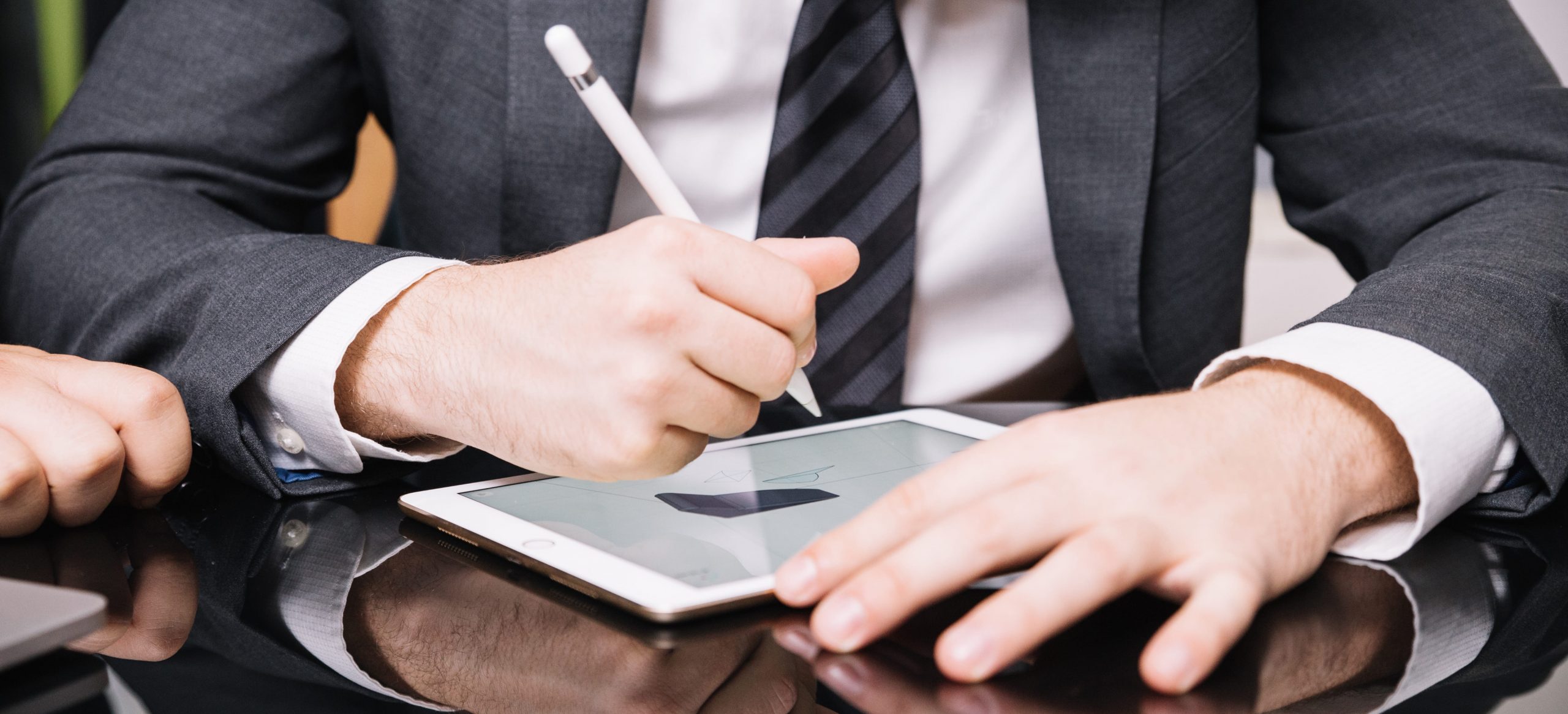 Homem usando terno e gravata, segurando um tablet e uma caneta para fazer assinatura digital usando certificado digital A3. O enquadramento da imagem está apenas no tronco do homem, sem mostrar seu rosto
